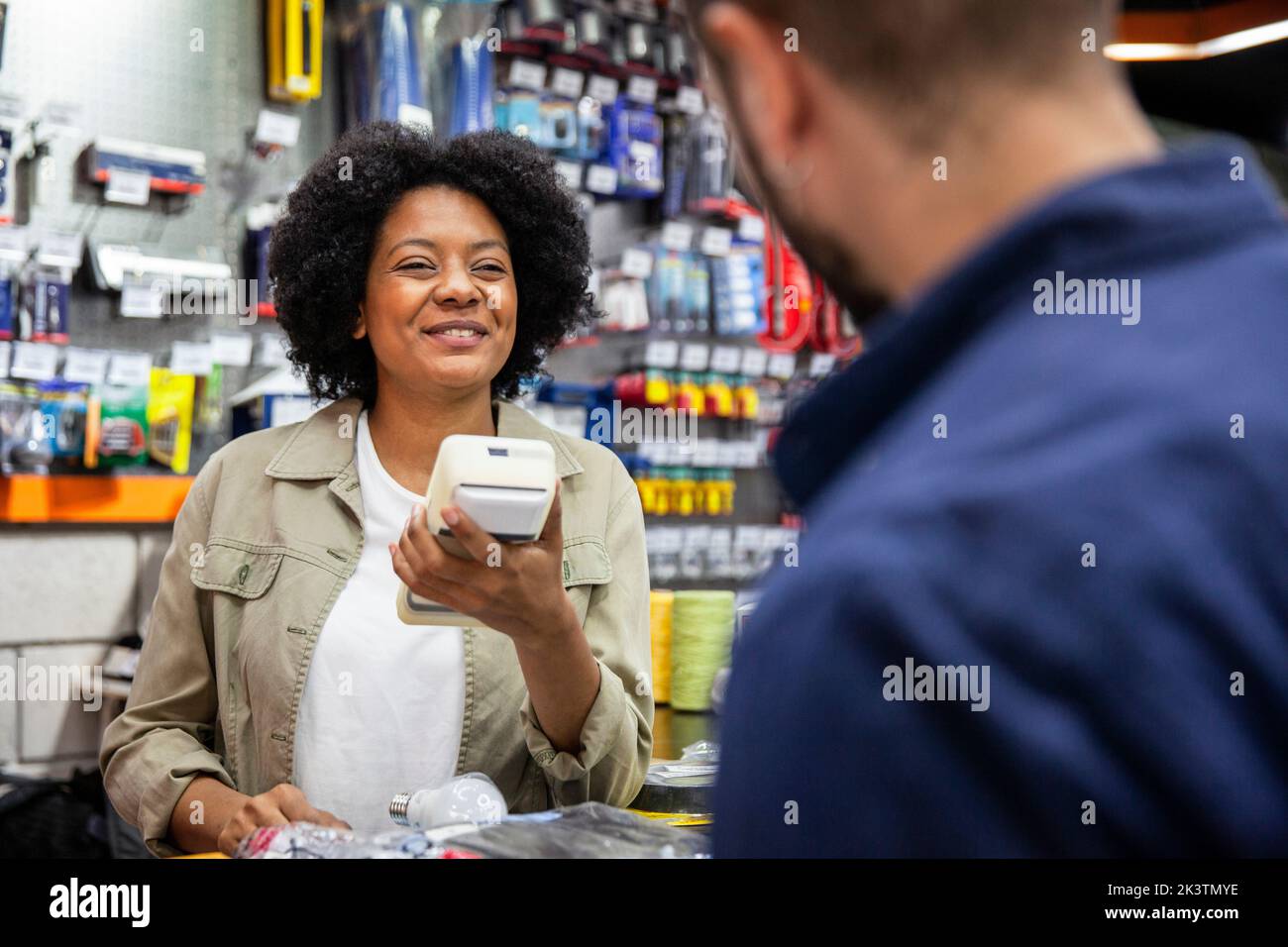 Cheerful African American hardware shop worker talking with male customer Stock Photo