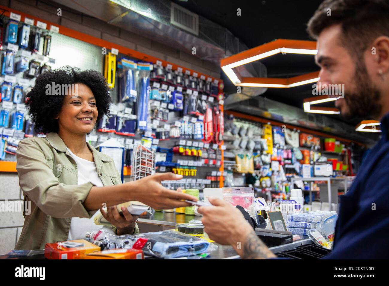 African American hardware shop worker charging on credit card to customer Stock Photo
