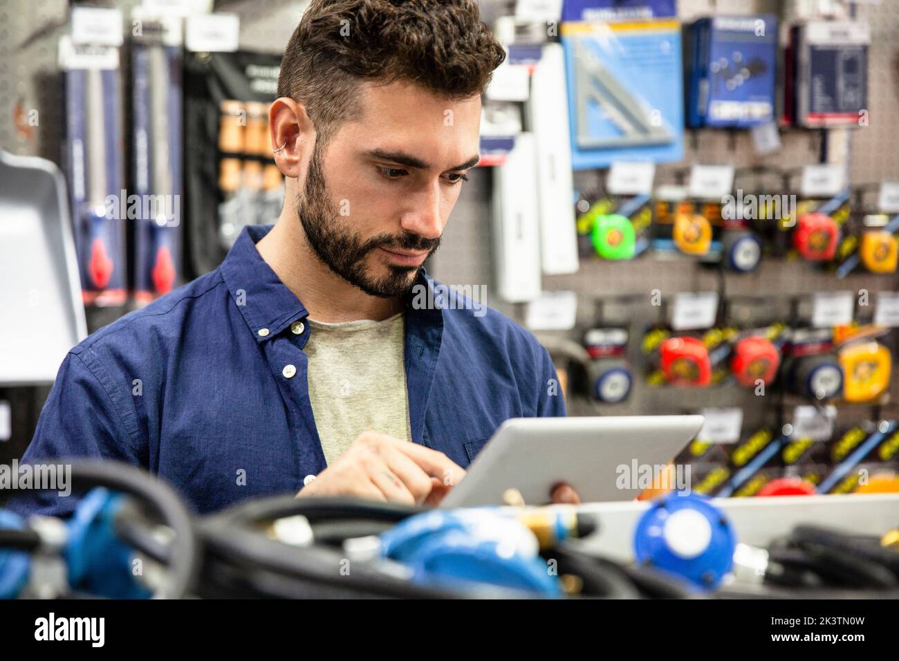 Male hardware shop owner taking inventory on digital tablet Stock Photo