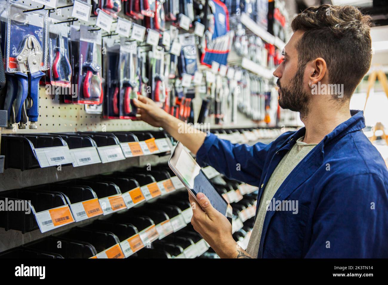 Male hardware shop worker setting prices on digital tablet Stock Photo