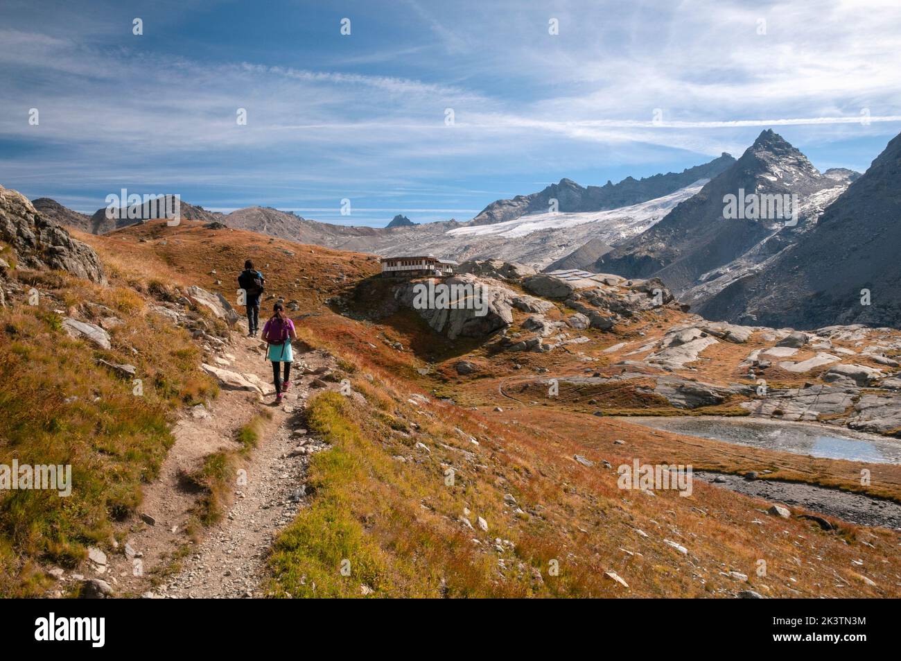 Young hikers with Evettes refuge (2590m) in the background, Haute-Maurienne, Vanoise mountain range, Bonneval-sur-Arc, Savoie (73), Auvergne-Rhone-Alp Stock Photo