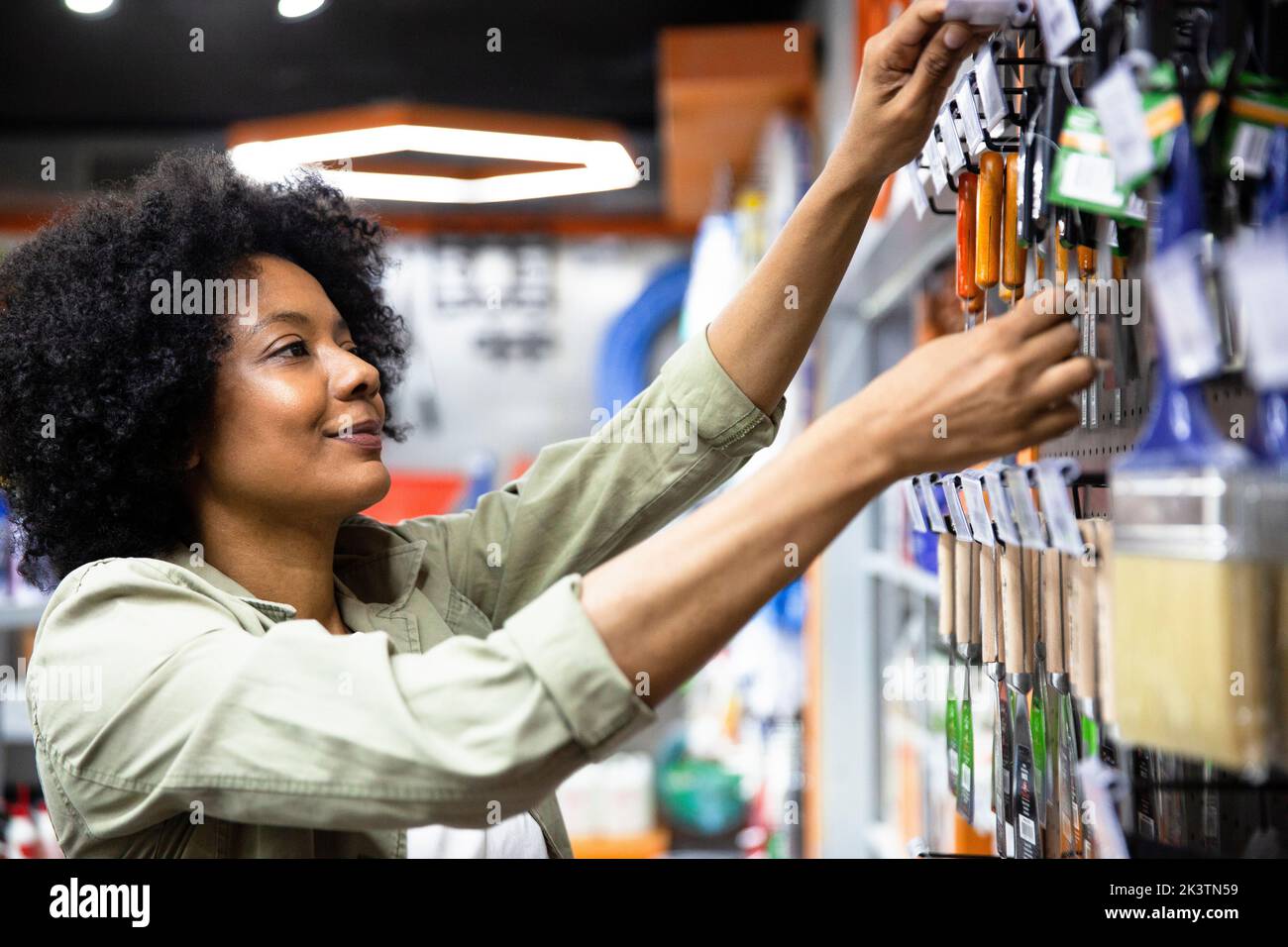 African American female hardware shop owner sorting out products on rack Stock Photo