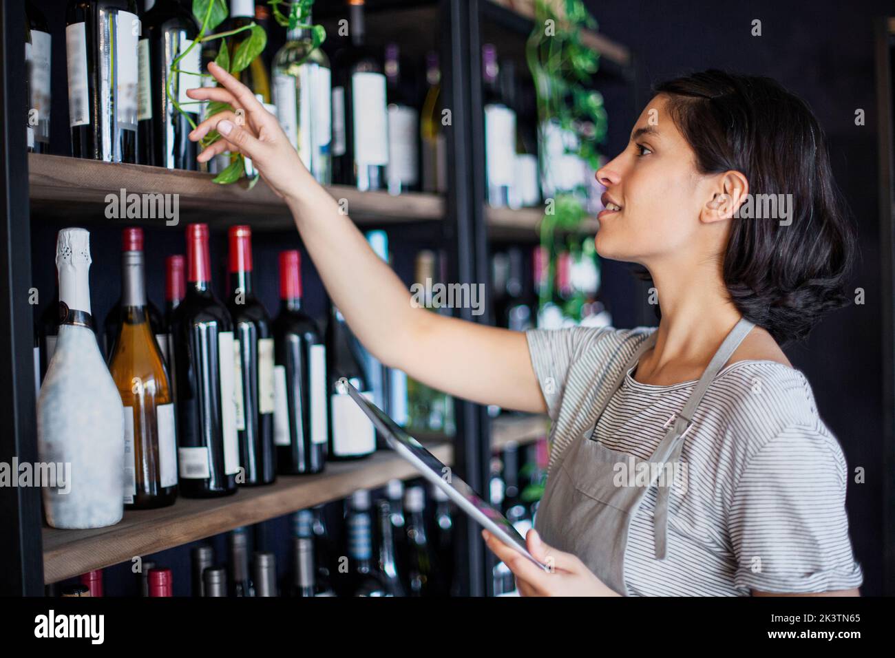 Wine store female worker setting prices in online store on digital tablet Stock Photo