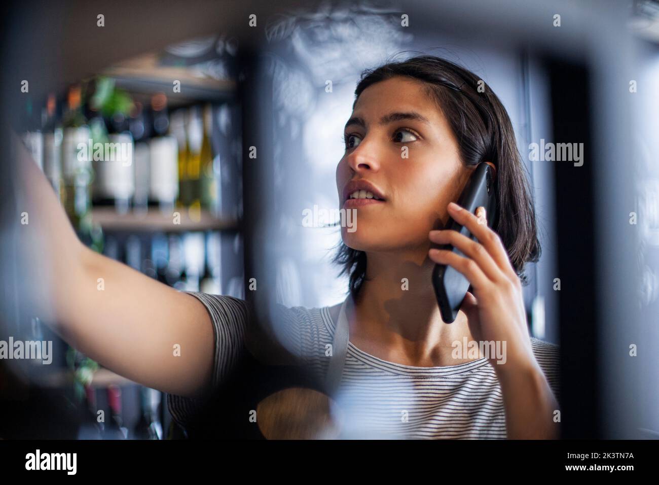 Wine store worker talking on smart phone Stock Photo