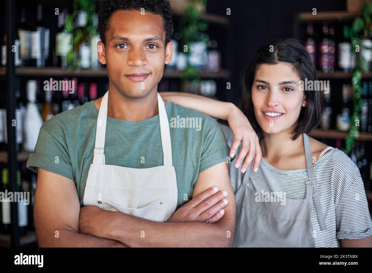 Wine store owner with arms crossed standing next to business partner