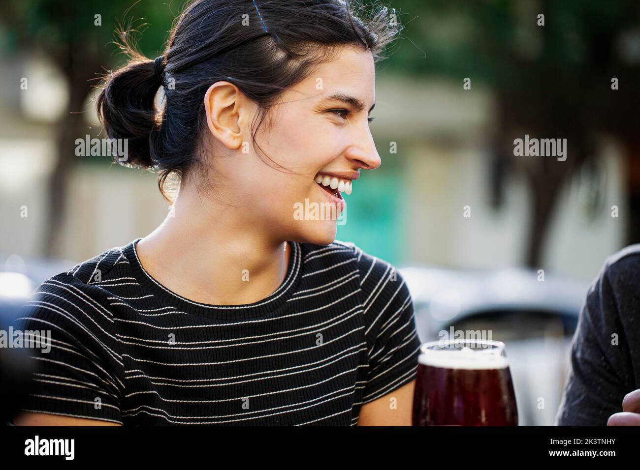 Close-up of smiling young woman sitting outdoors Stock Photo