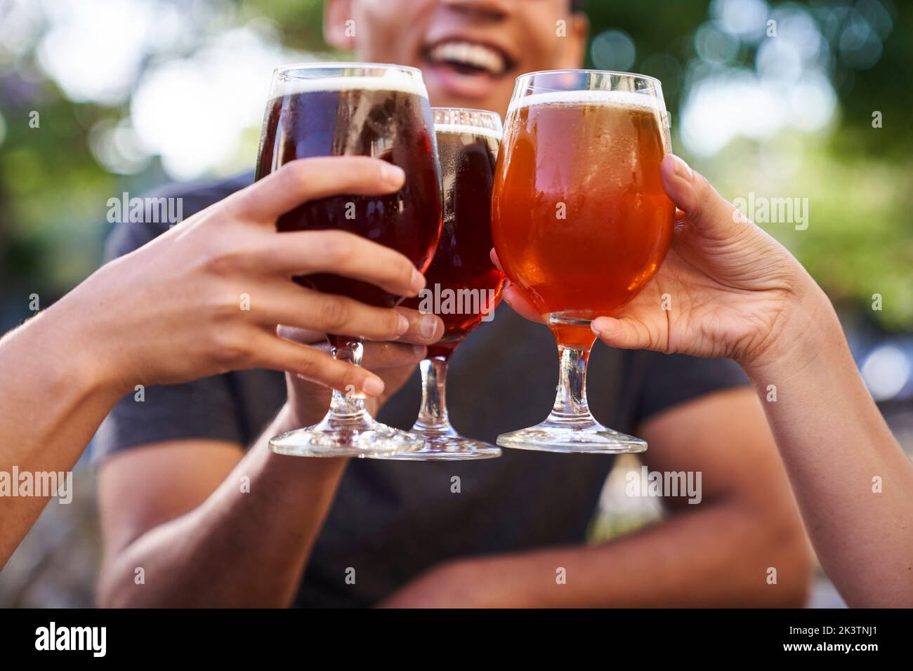 Mid-shot of three glasses of beer being raised in a toast Stock Photo