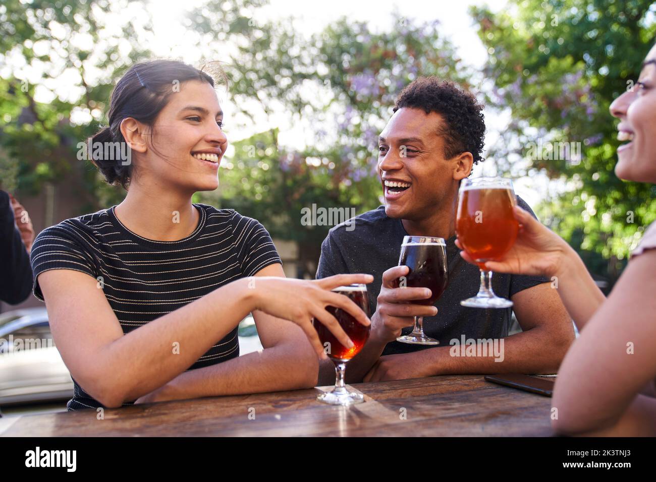 Mid-shot of young Latin-American woman and her diverse group of friends enjoying craft beer Stock Photo