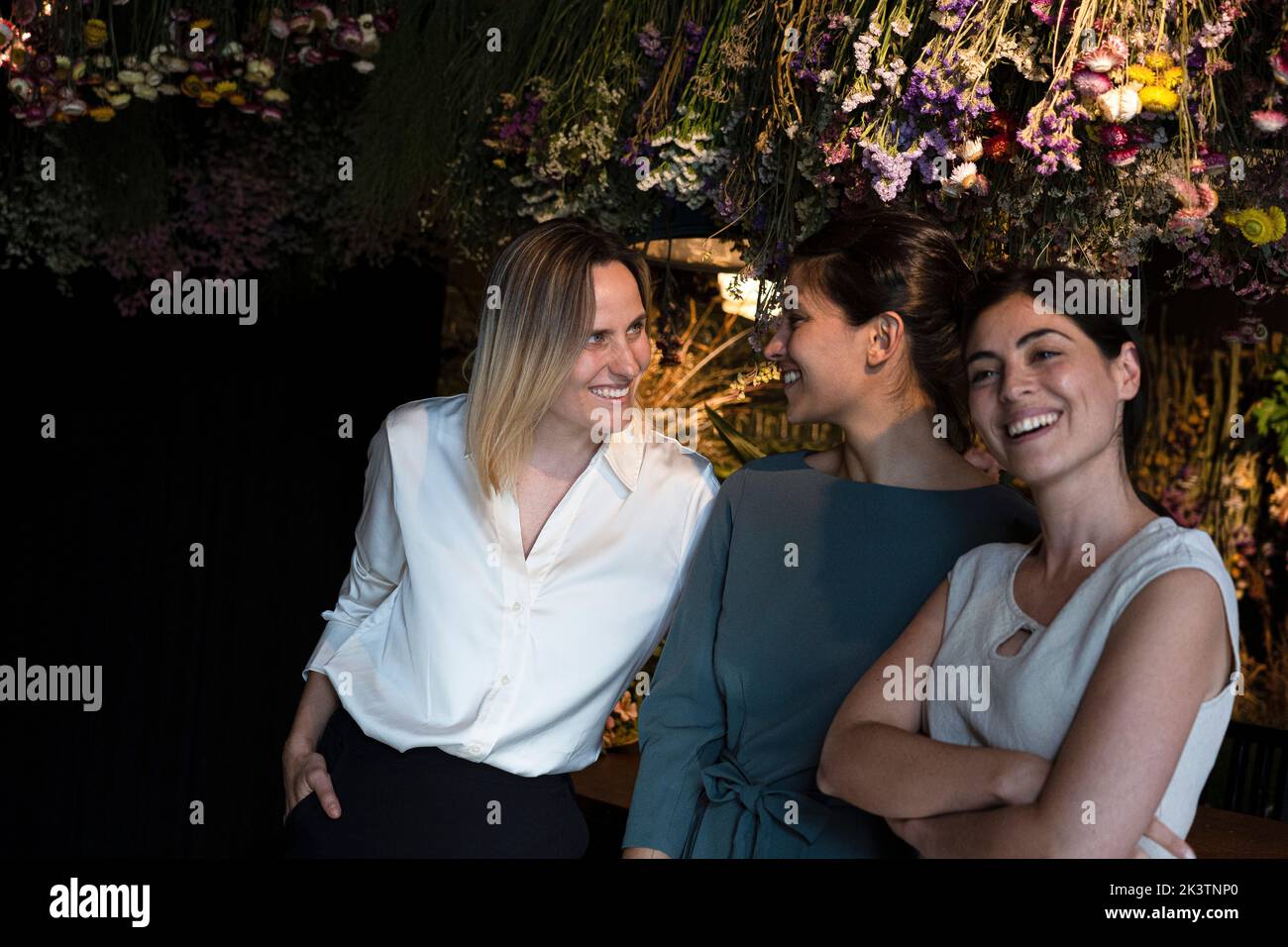 Group shot of three ethnically diverse girl friends smiling at camera while hanging out at night Stock Photo