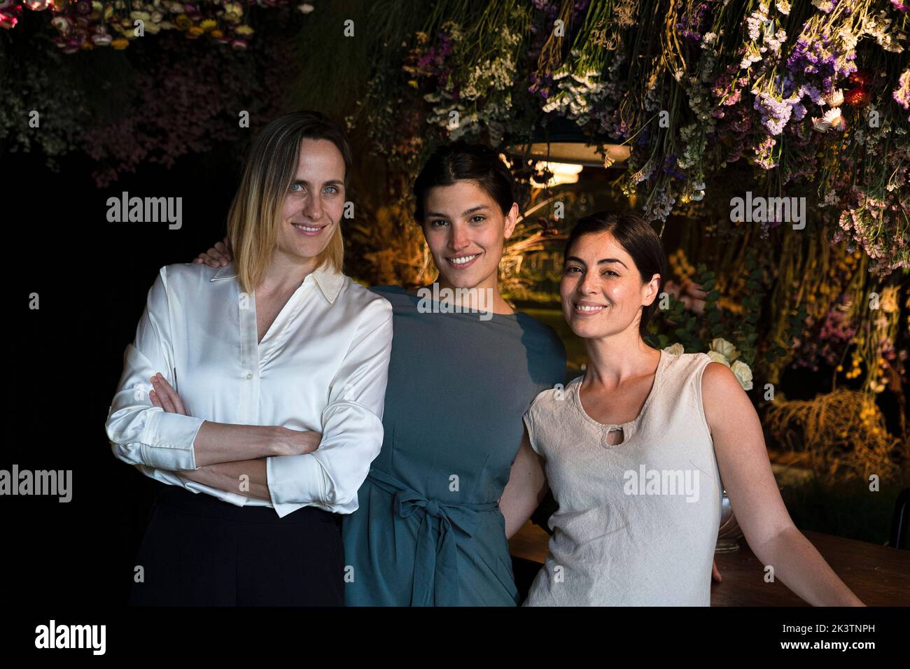 Group shot of three ethnically diverse girl friends smiling at camera while hanging out at night Stock Photo