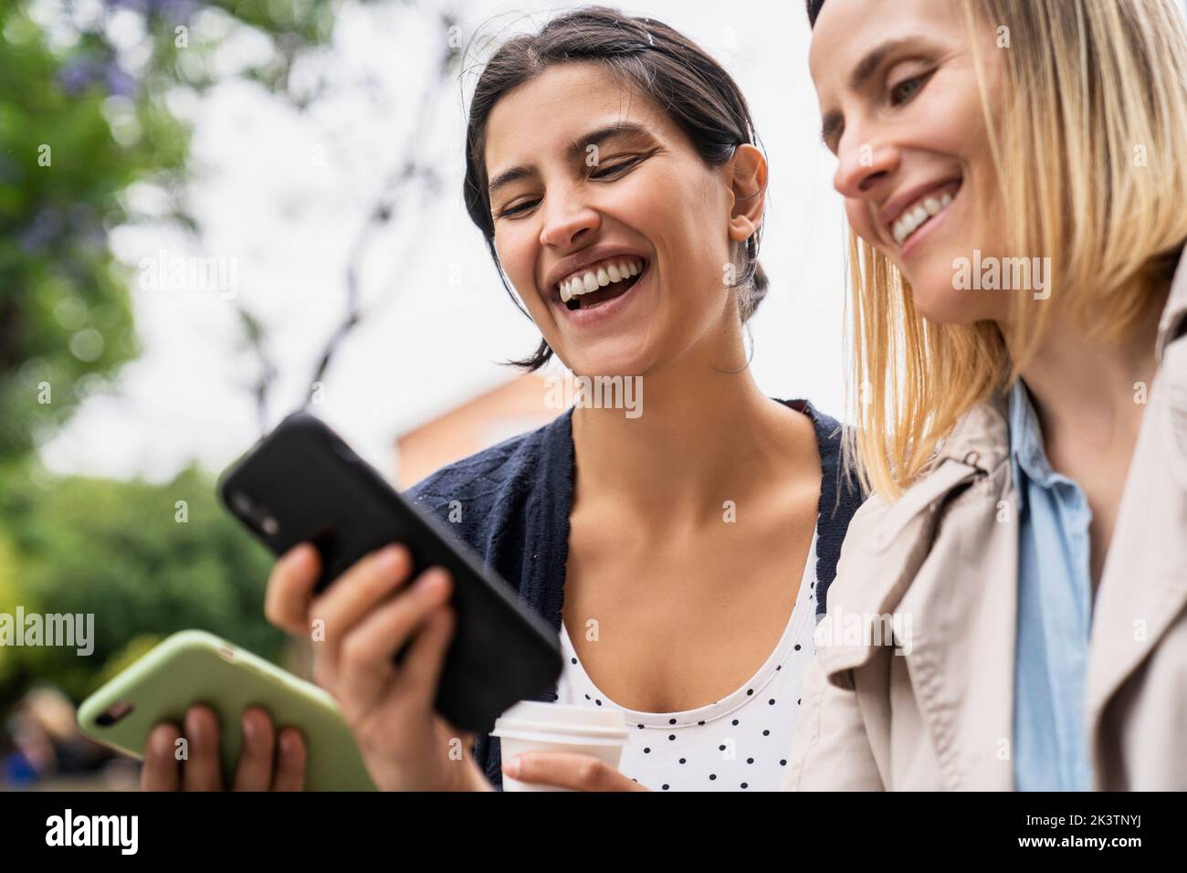Low angle side view of two female digital nomads having fun with content found on their social media Stock Photo