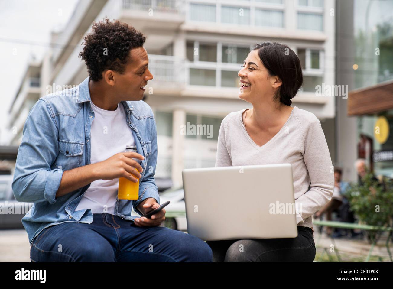 Mid-shot of diverse couple of co-workers discussing business matters while working outdoors Stock Photo