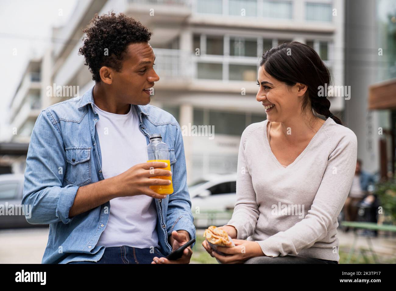 Young African-American man and Latin-American woman having a snack outdoors and enjoying themselves Stock Photo