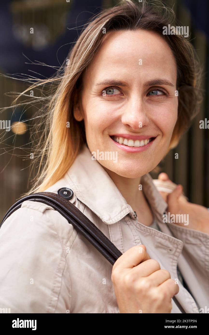 Mid-shot of smiling lady with handbag looking into the distance Stock Photo