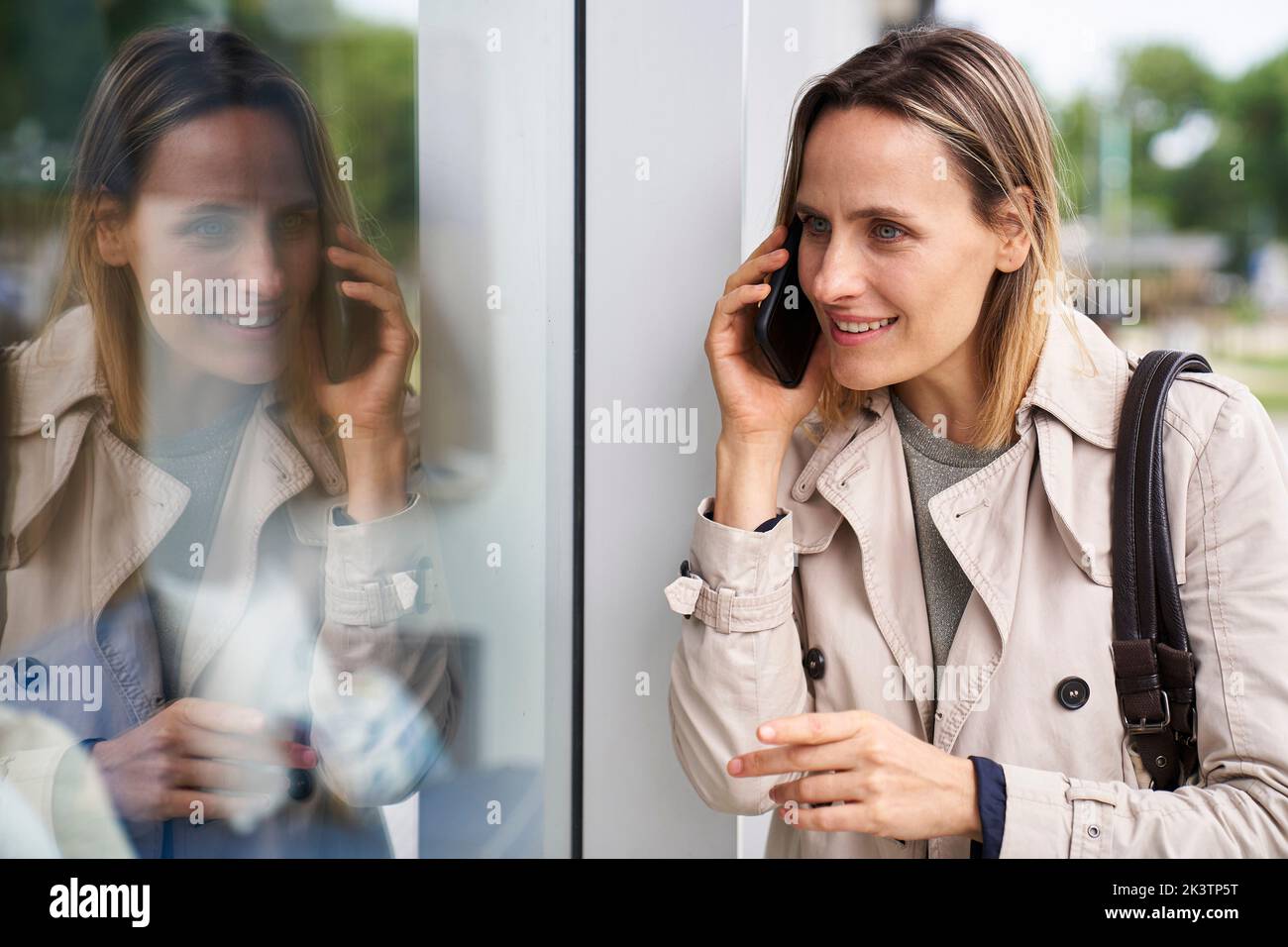 Medium shot of woman and her reflection on shop window Stock Photo