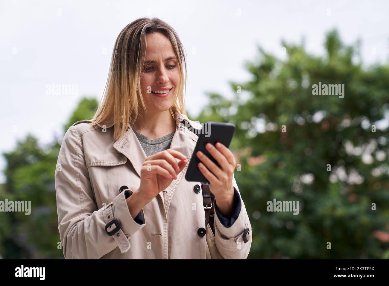 Attractive woman looking at her cell phone while walking in the street Stock Photo