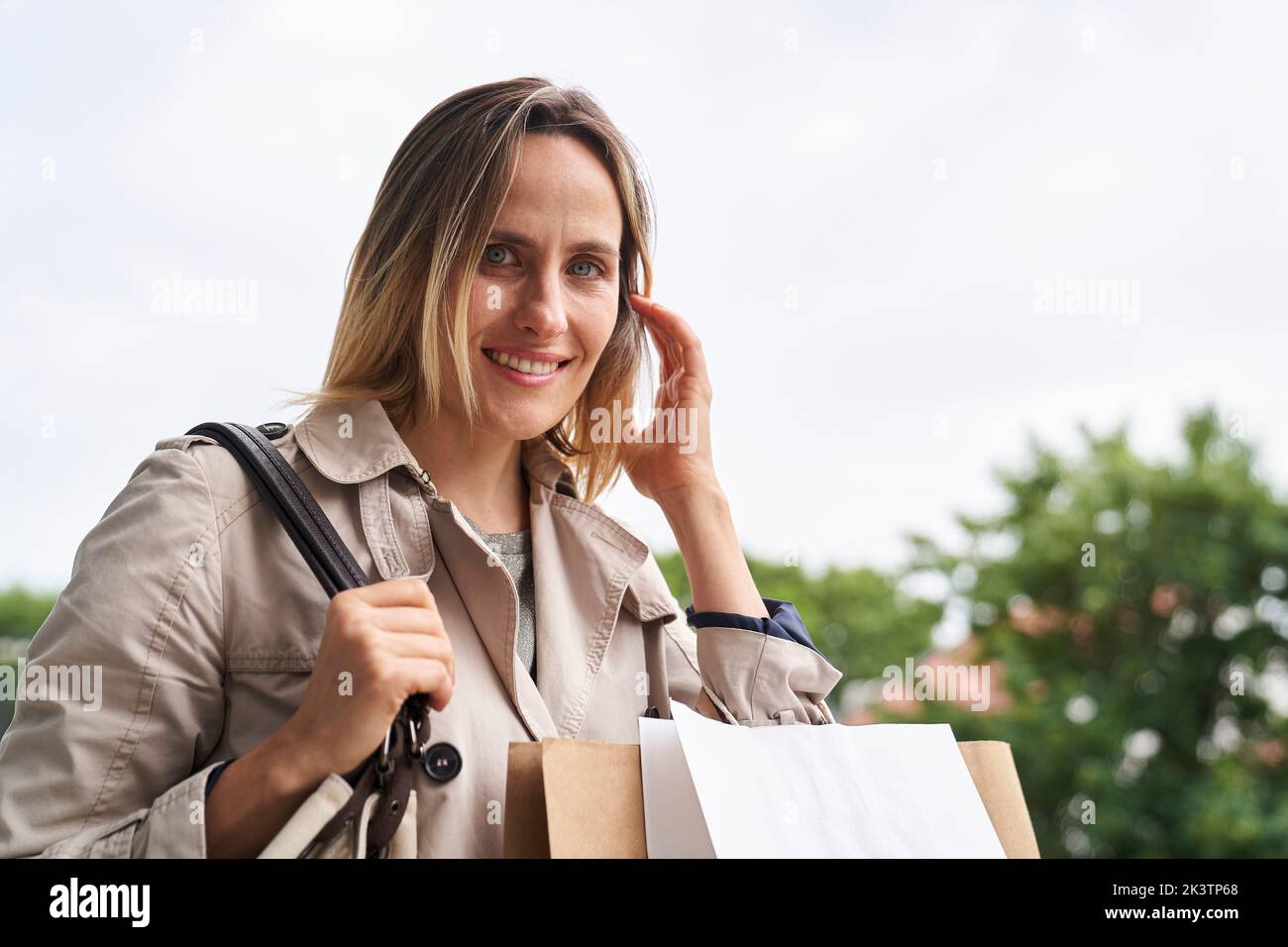 Medium shot of woman walking in the street with shopping bags Stock Photo