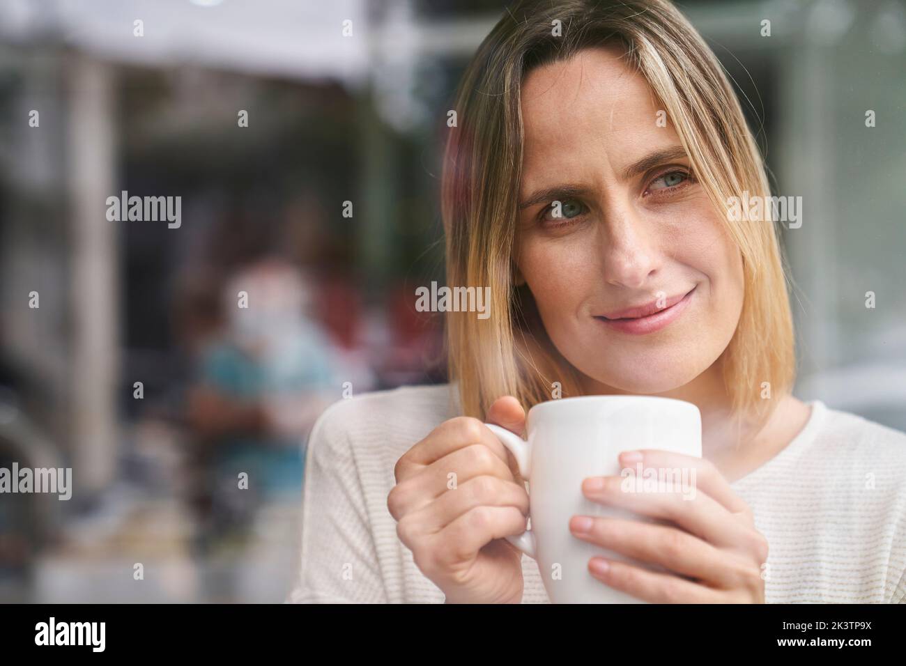 Mid-shot portrait of attractive woman holding a cup of coffee and enjoying the moment Stock Photo