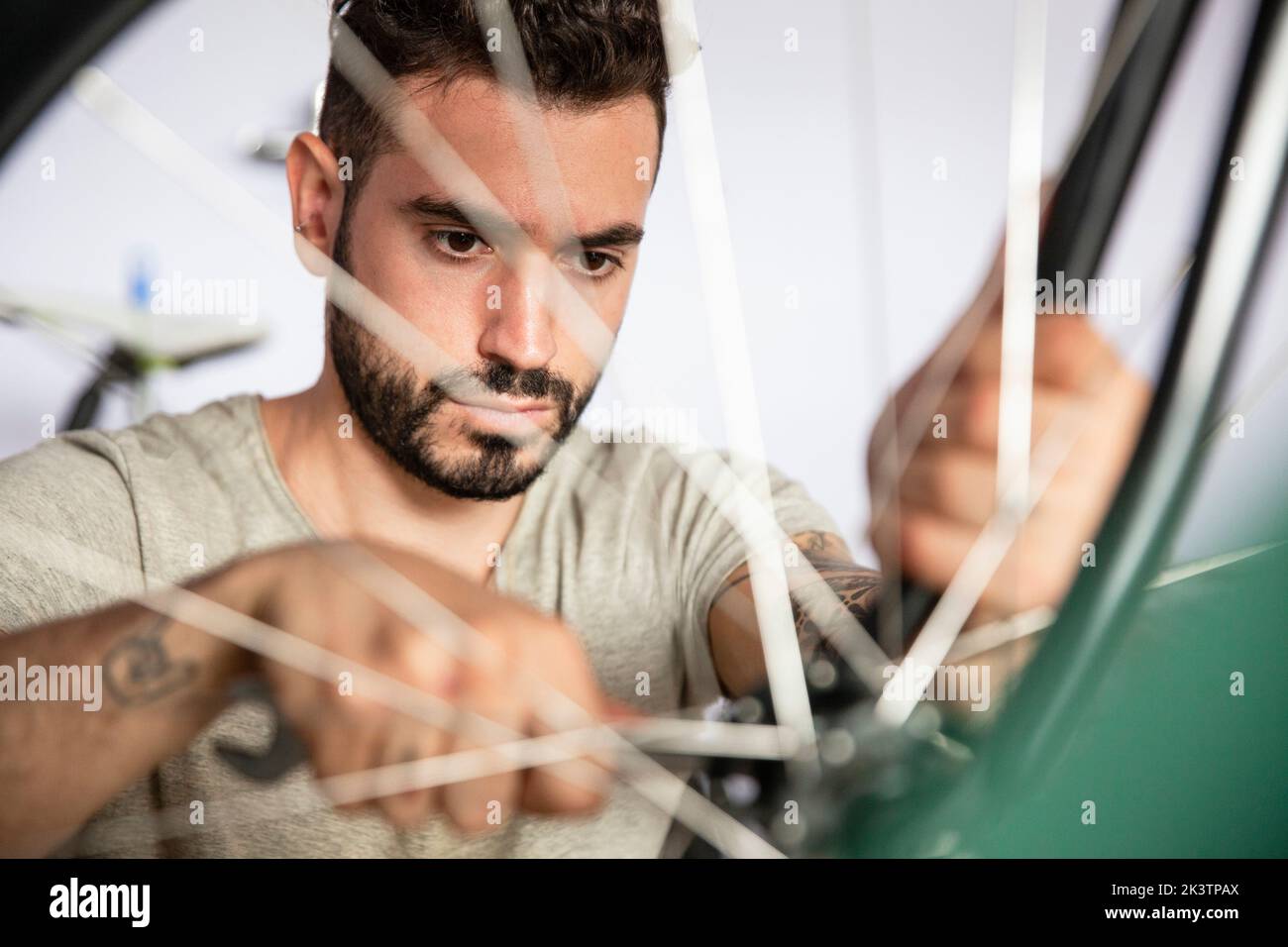 Young adult mechanic reparing bicycle wheel Stock Photo