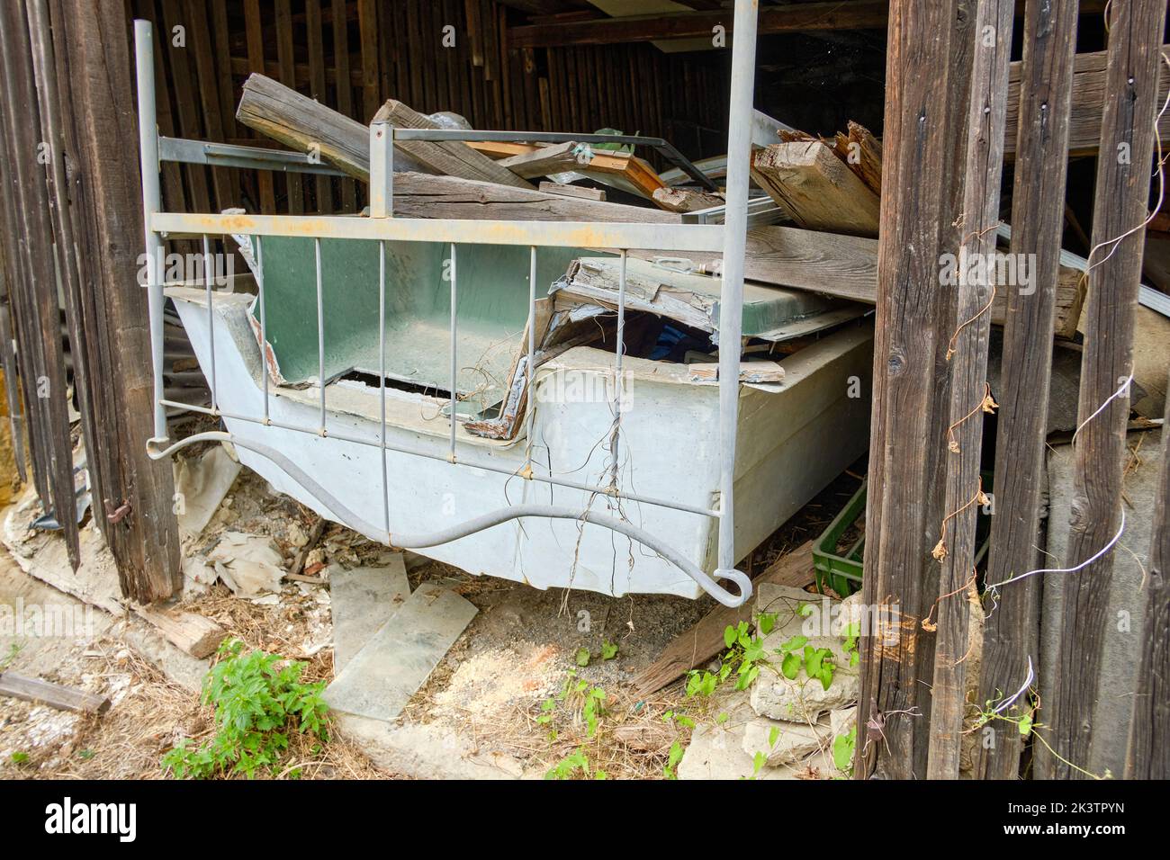 Neglected plastic boat full of junk in a derelict barn. Stock Photo
