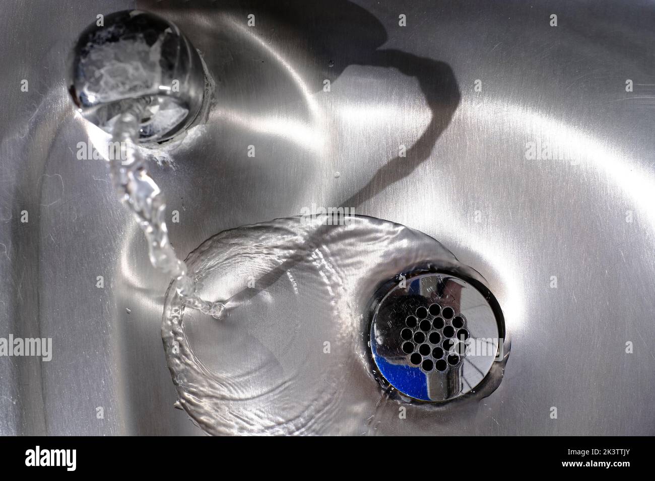 Steel metal shiny sink with water flowing down the drain Stock Photo