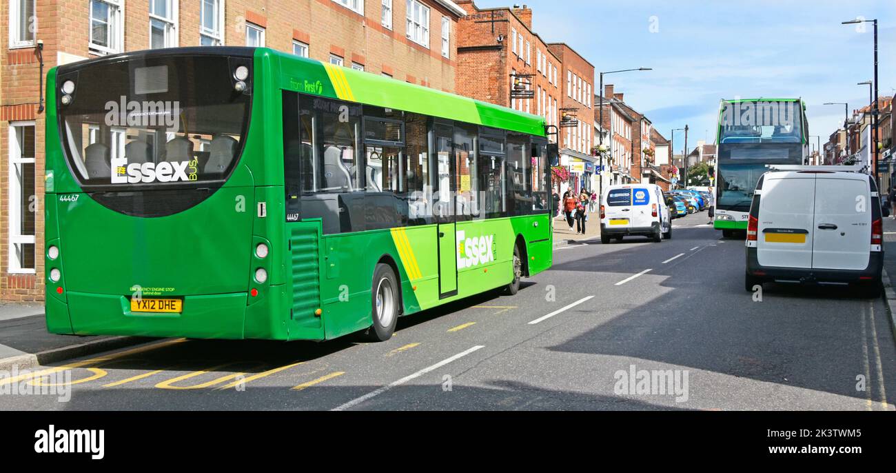 Public transport services traffic in sunny Witham town shopping street scene close up green First Essex single decker bus & double decker  England UK Stock Photo