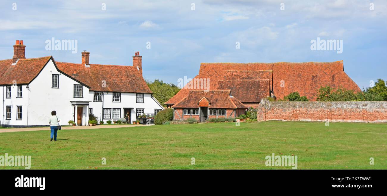 Historical structures in spacious Cressing Temple Barns medieval site L-R  grade ii listed Farm House Wheat Barn building & Tudor Garden Wall Essex UK Stock Photo