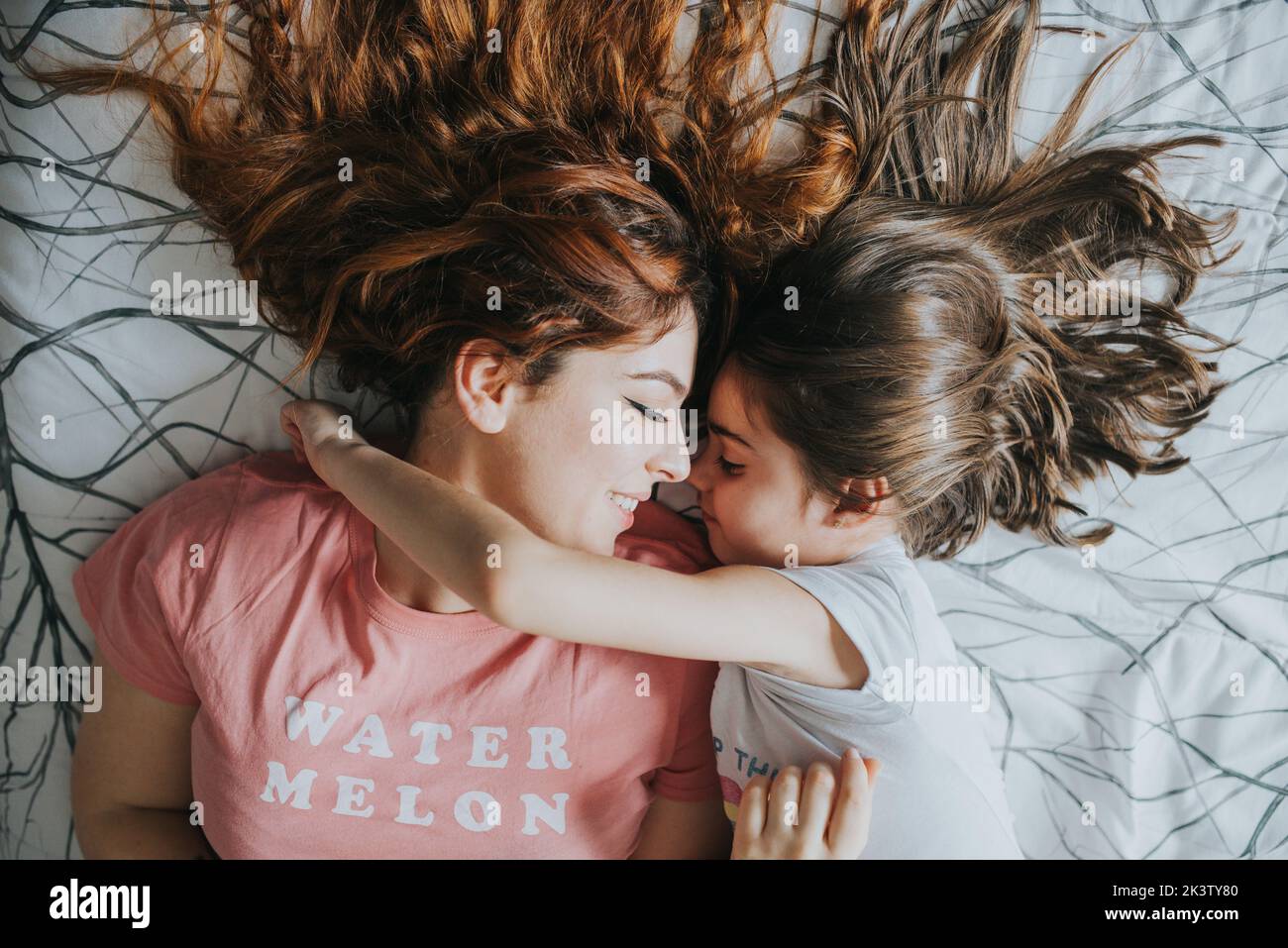 From above young elder sister and funny kid in pajamas looking at each