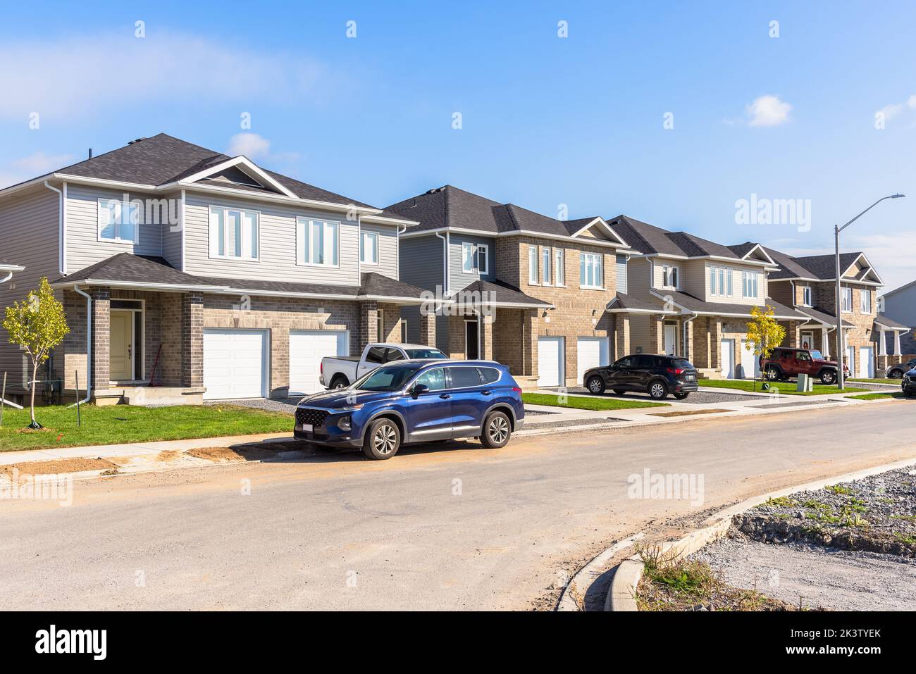 New semi-detached houses along a street in a housing development on a sunny autumn day Stock Photo
