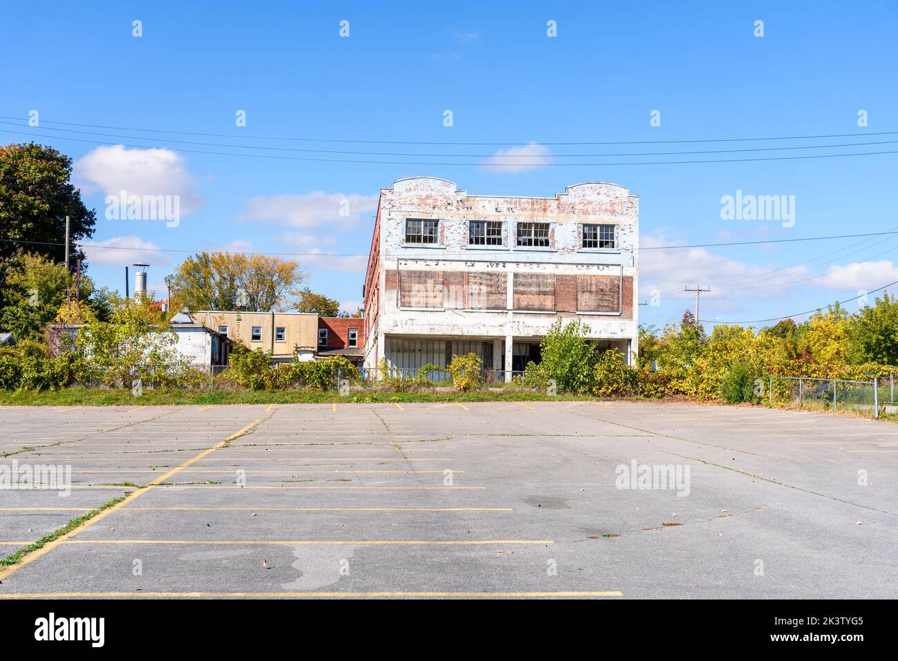 Empty parking lot bordered by old abandoned buildings on a clear autumn day Stock Photo