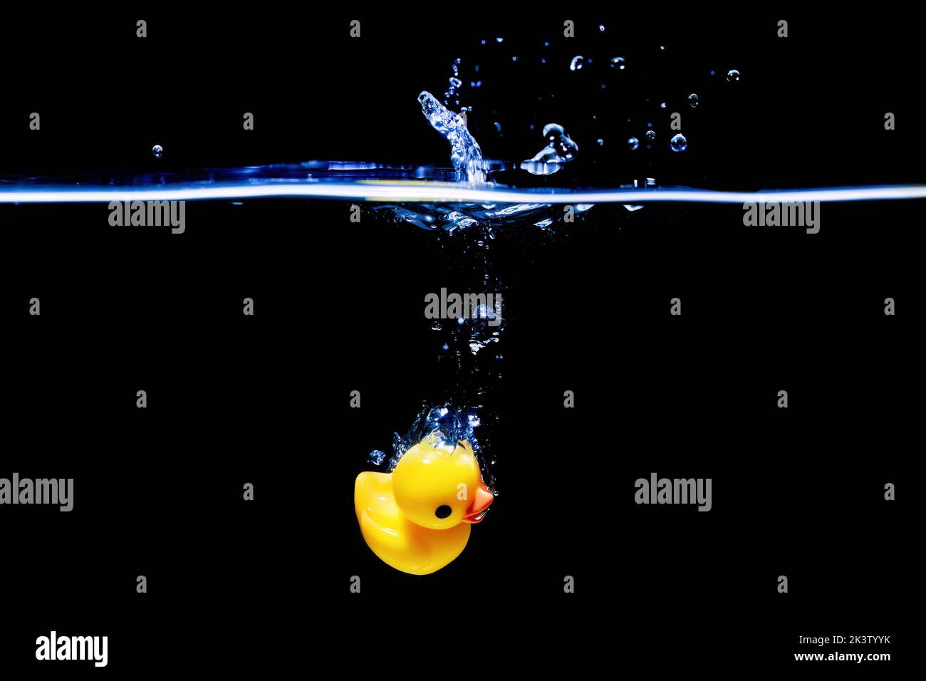 Yellow rubber duck sinking underwater in a transparent water tank