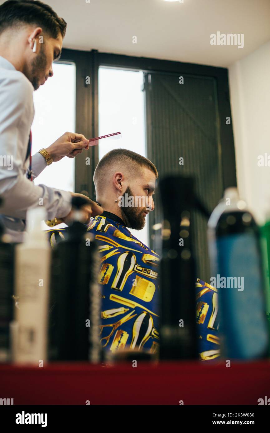 A barber cuts the hair of a customer with a clipper Stock Photo - Alamy