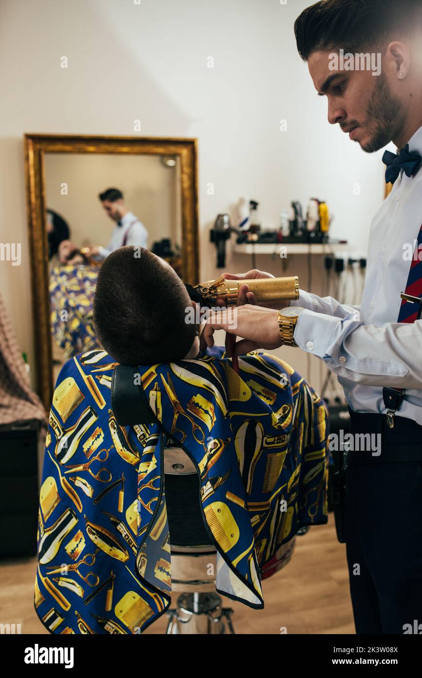 A barber cuts the beard of a man with a clipper in a barbershop Stock Photo