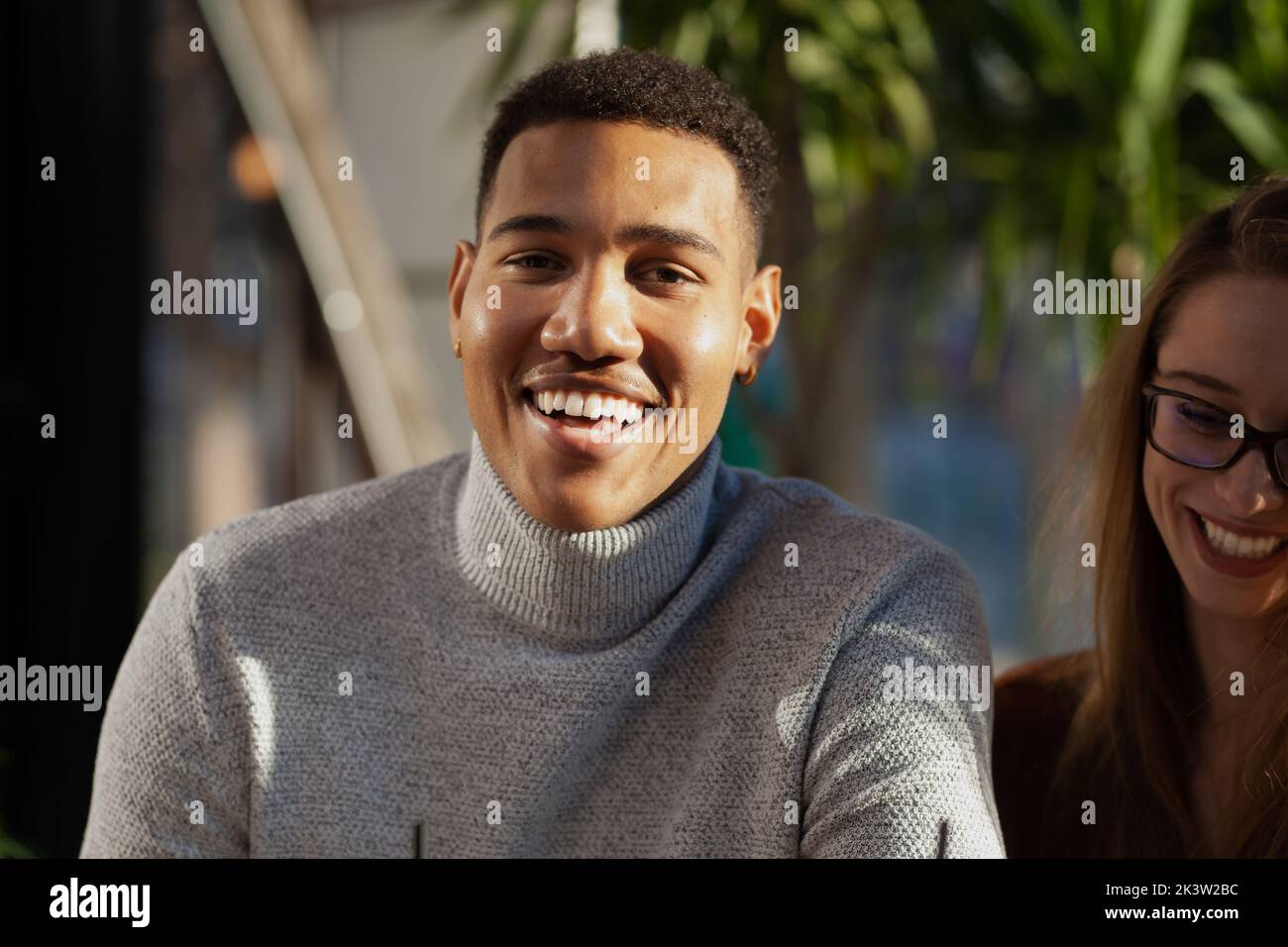 Two multiracial friends smiling in a bar. Afterwork meeting after successful work day. Stock Photo