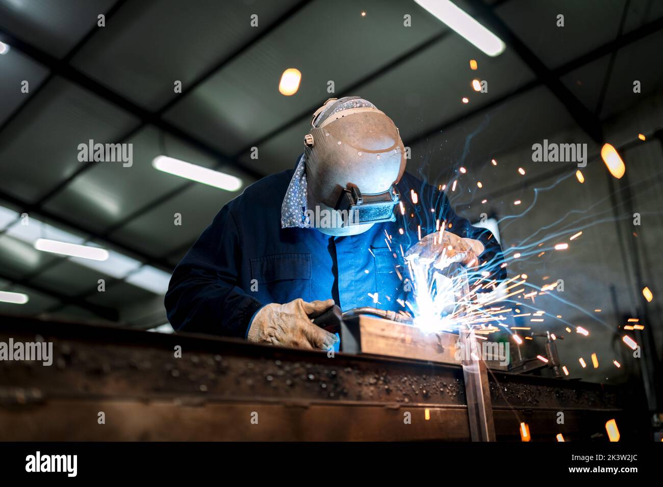 Man Using Wielding Machine Unrecognizable male employee in protective gloves and helmet using ...