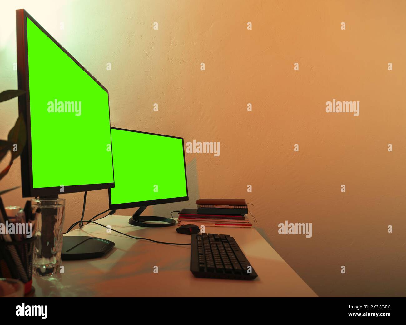 White office desk with two monitors on it green screens turned on for copy space. Stock Photo