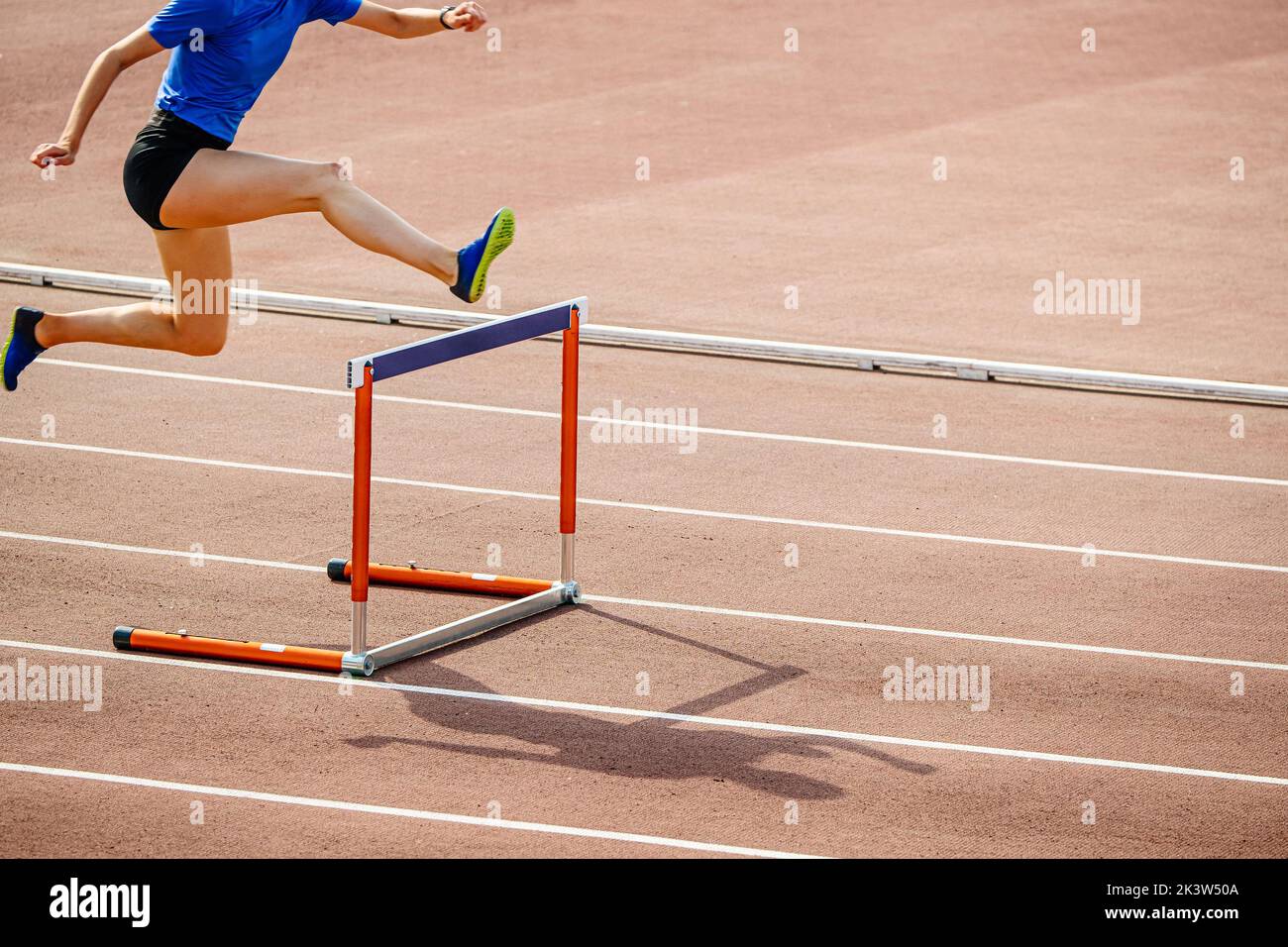 female athlete hurdling at stadium Stock Photo