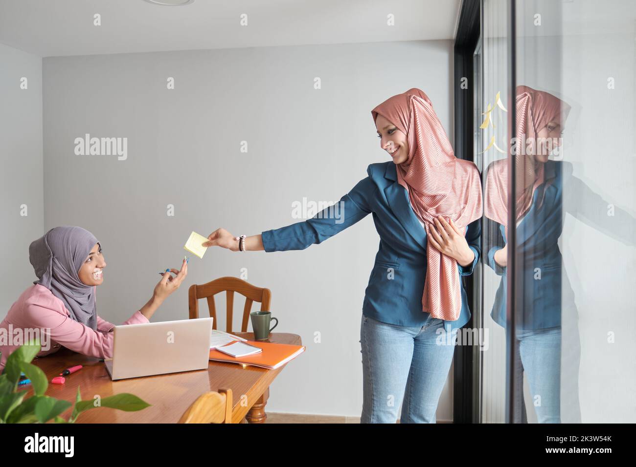 Two muslim women using sticky notes on windows to plan a marketing strategy. Stock Photo