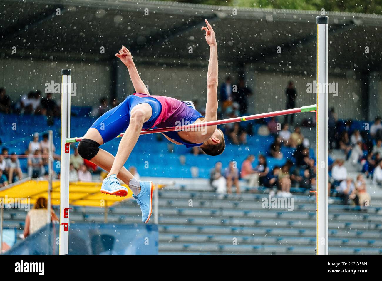 male athlete high jump in rain Stock Photo