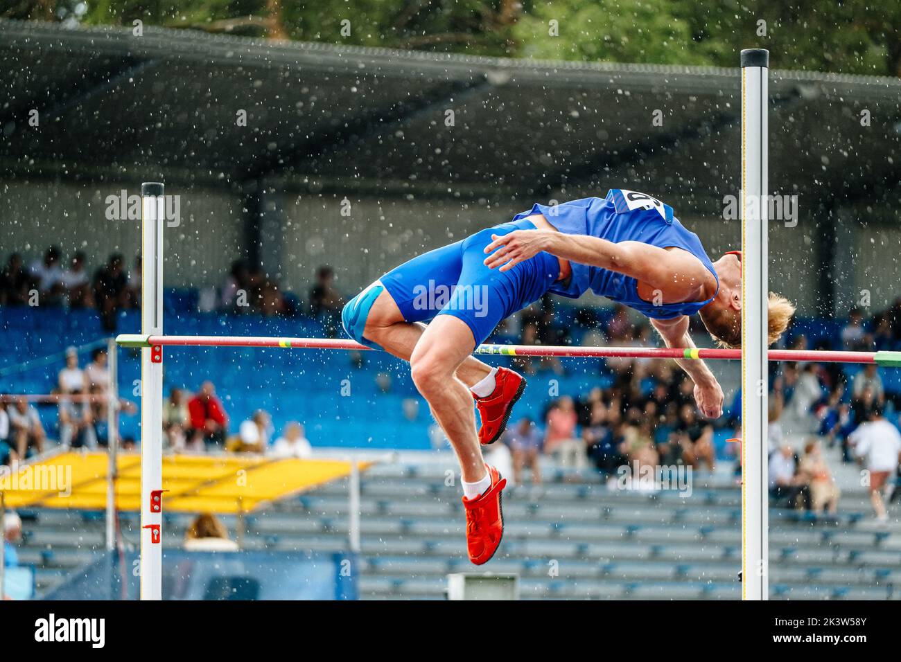 unsuccessful attempt athlete high jump in rain Stock Photo