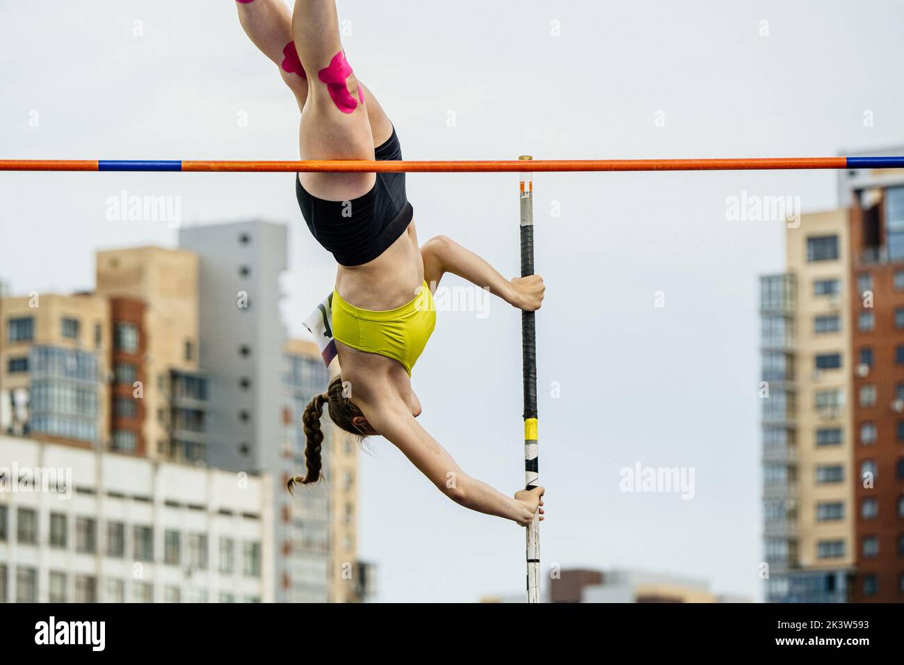 close-up female athlete pole vault on background of buildings Stock Photo