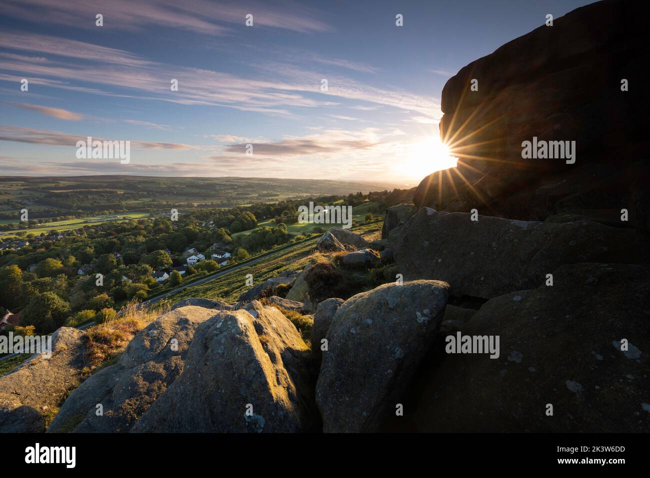 Sunrise on the famous Cow and Calf rocks, Ilkley moor, with the West Yorkshire town of Ilkley and Wharfedale in the distance. Stock Photo