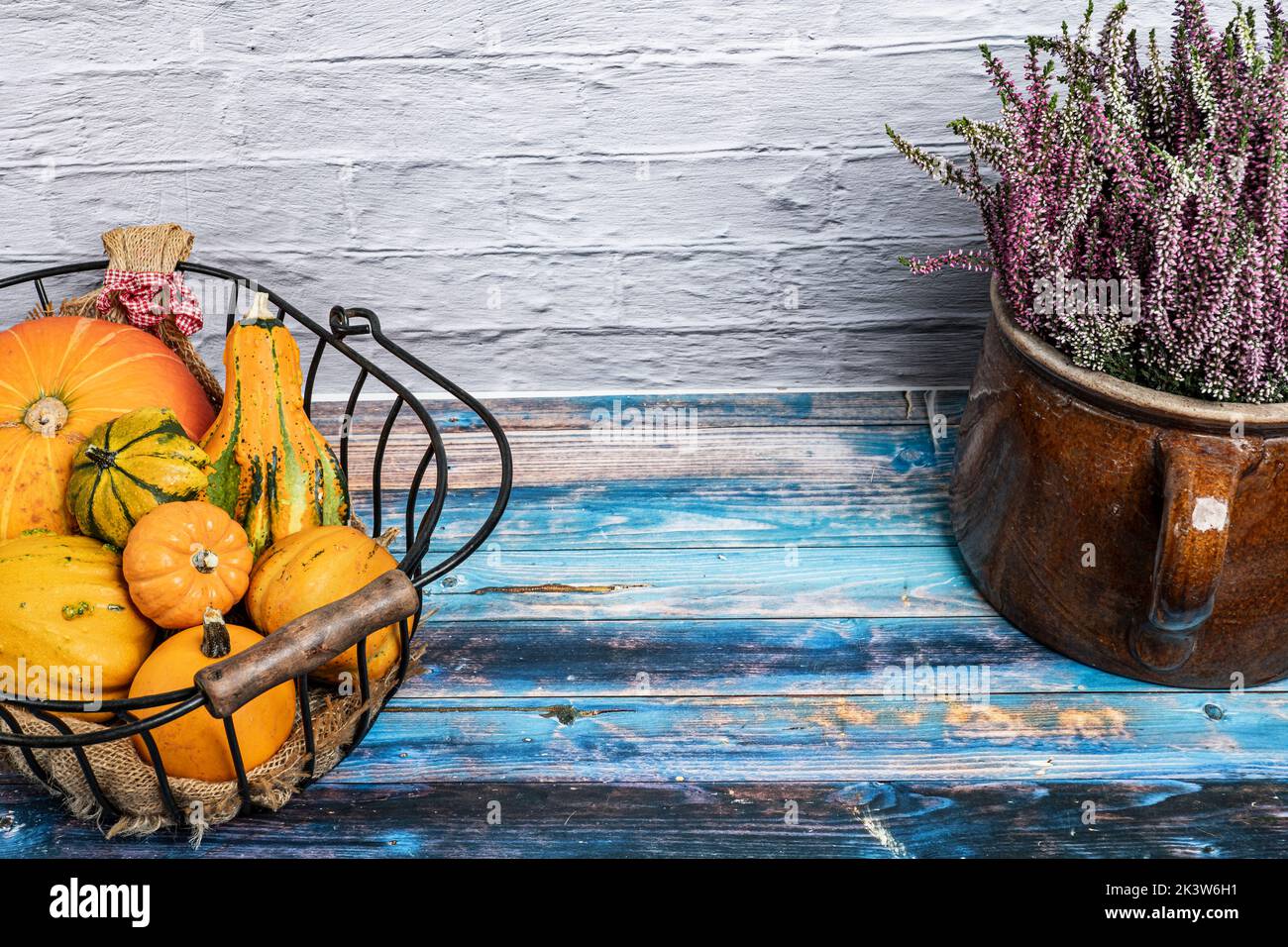 various ornamental gourds in an old wire basket decorated with winter heather Stock Photo