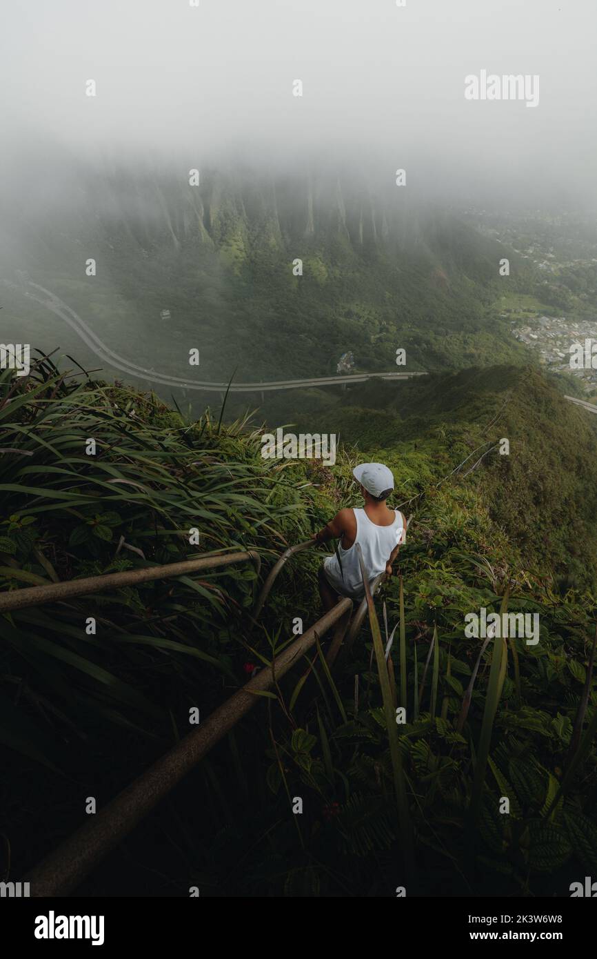 A vertical shot of a man hiking on the Haiku Stairs in Oahu, Hawaii Stock Photo