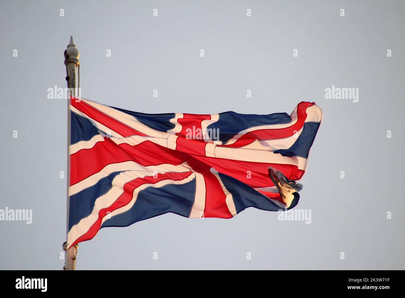 A Union Jack flag waving in the wind on the blue sky background Stock ...
