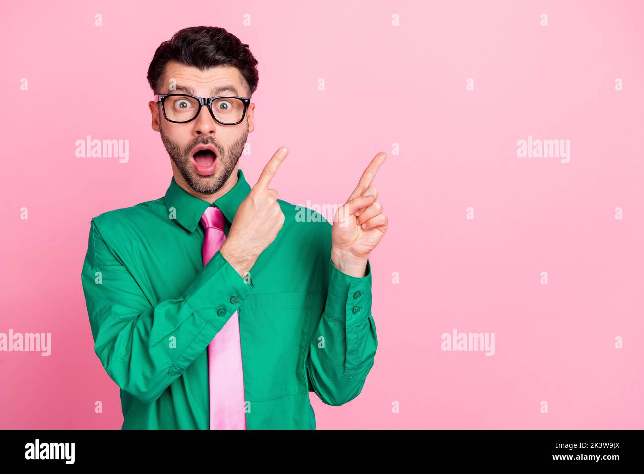 Closeup photo of young funny surprised guy pointing fingers empty space wow how no idea isolated on pink color background Stock Photo