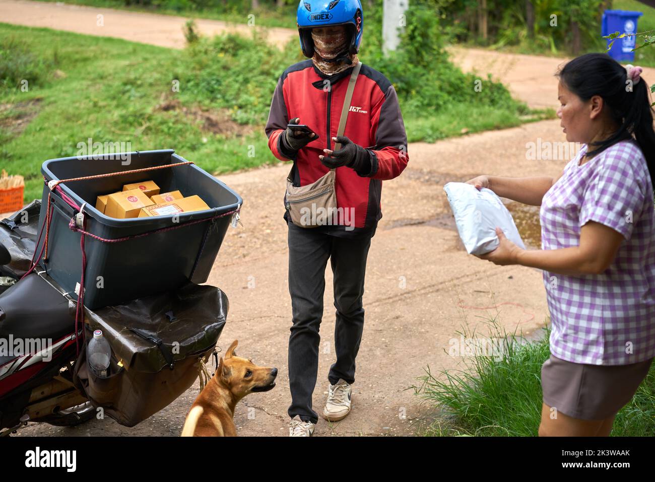 A motorcycle courier delivers packages in a rural area. Stock Photo