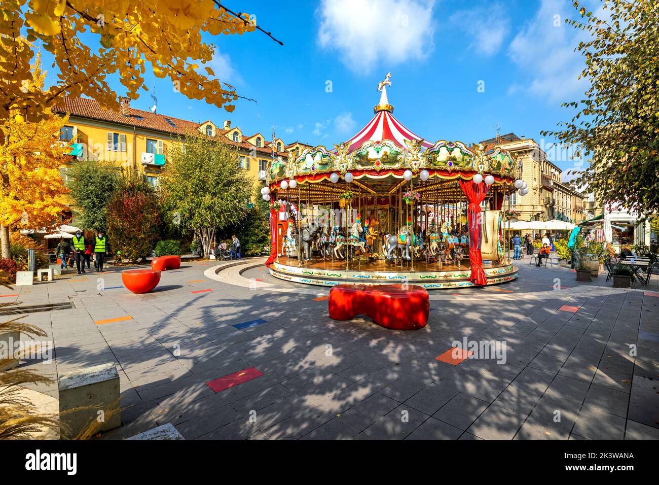 Carousel on the town square surrounded under blue sky in Alba - small town in Piedmont region in Northern Italy. Stock Photo
