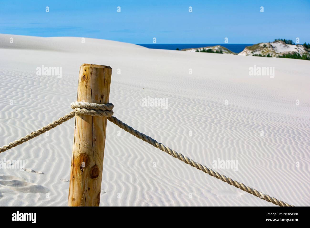 Sand Van Rope Wooden and rope fence at Leba sand desert in Poland with sea horizon ...