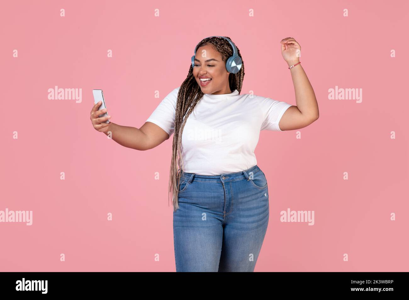 African Lady Listening Music Holding Smartphone Wearing Earphones, Pink